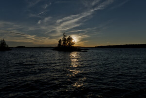 Sun setting behind a small island. Sky shows various colors. Sun setting behind a small island. Sky shows various colors.