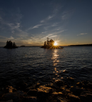 Sun setting behind a small island. The sun is reflecting on the water leading directly to the viewer. Sun setting behind a small island. The sun is reflecting on the water leading directly to the viewer.